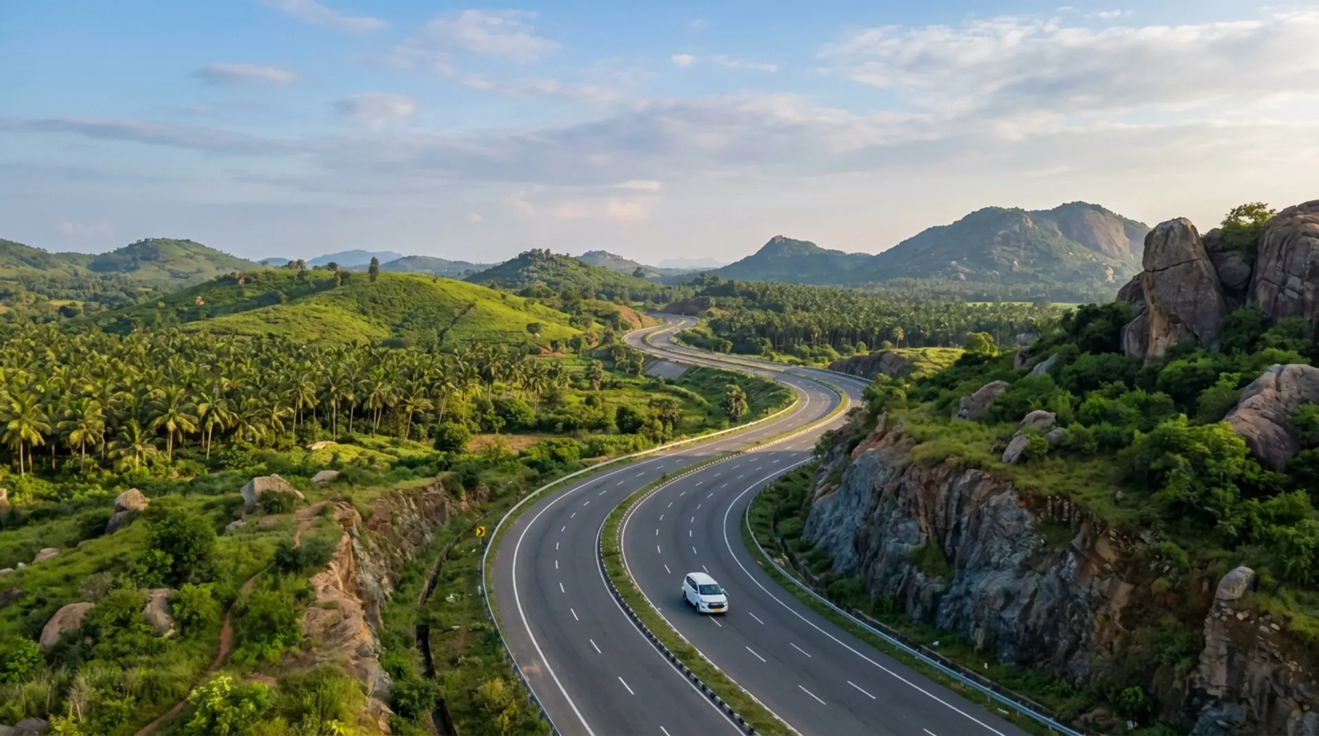 Aerial view of a winding highway through green hills with a cab on the road